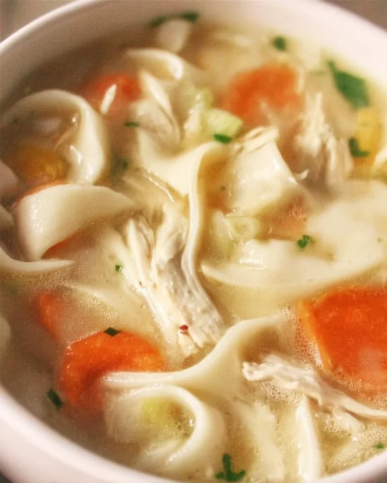 Bols de soupe au poulet et nouilles chaudes garnies d'herbes fraîches.