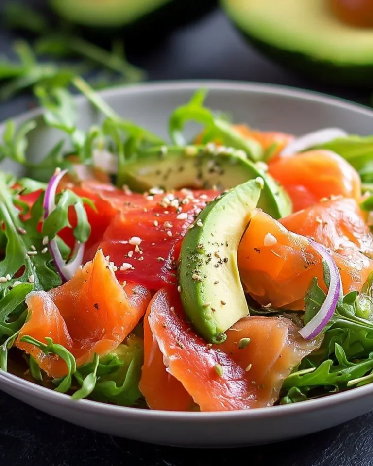 Salade de saumon fumé et avocat sur une assiette, garnie de légumes frais.
